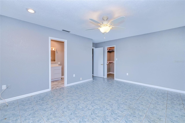 unfurnished bedroom featuring a walk in closet, ceiling fan, a textured ceiling, connected bathroom, and a closet