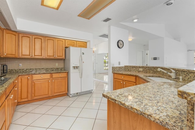 kitchen featuring light stone countertops, white fridge with ice dispenser, sink, backsplash, and light tile patterned floors