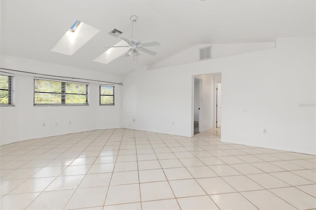 spare room featuring lofted ceiling with skylight, light tile patterned flooring, and ceiling fan