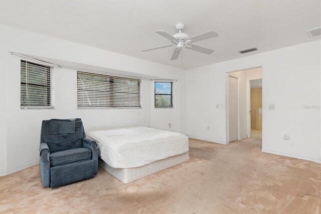 bedroom featuring a textured ceiling, ceiling fan, and light carpet