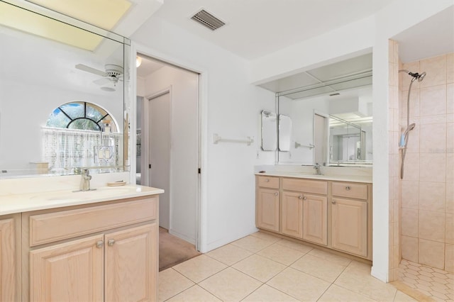 bathroom featuring tile patterned floors, ceiling fan, vanity, and a tile shower