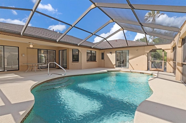 view of pool featuring glass enclosure, ceiling fan, and a patio