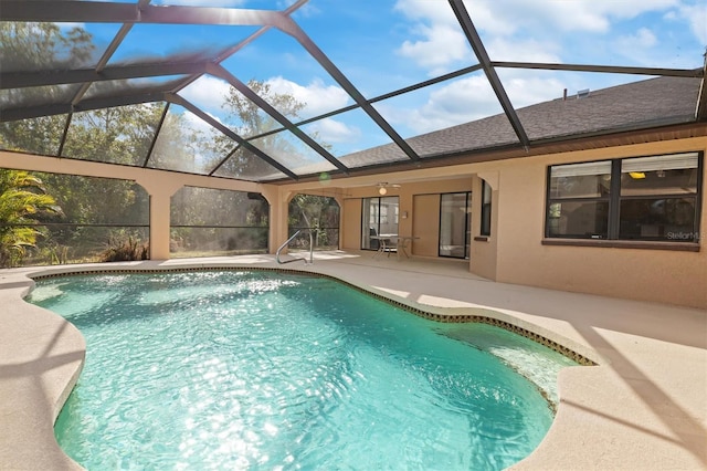 view of pool with glass enclosure, ceiling fan, and a patio area