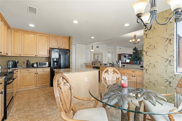 kitchen with pendant lighting, light stone counters, an inviting chandelier, and black appliances