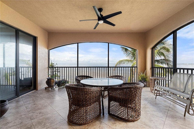 sunroom / solarium with a water view and ceiling fan