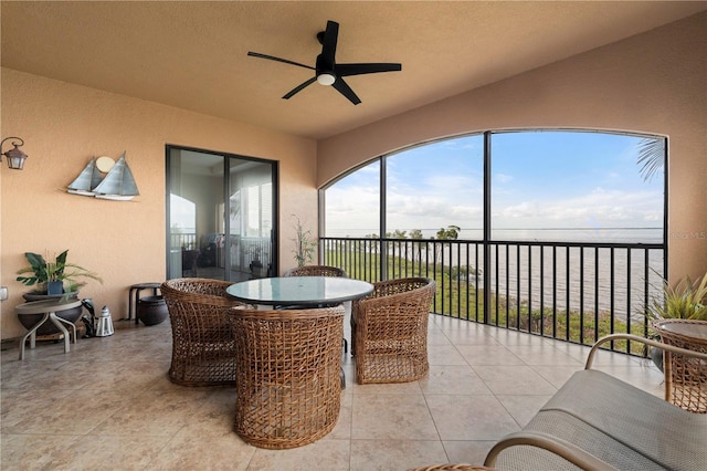 sunroom / solarium with ceiling fan and a water view