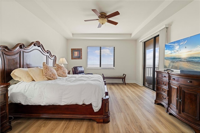 bedroom with ceiling fan, a tray ceiling, access to outside, and light hardwood / wood-style flooring