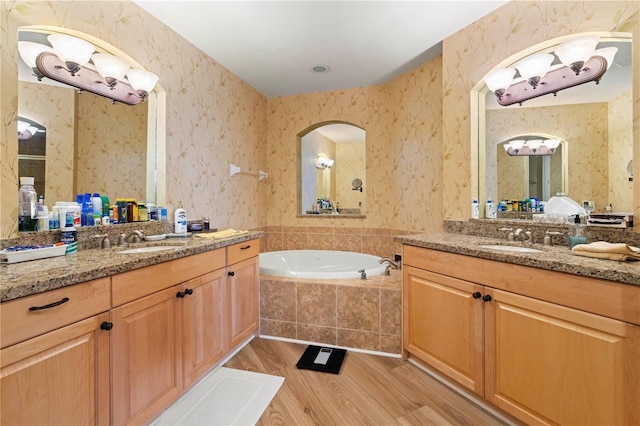 bathroom with tiled bath, vanity, and hardwood / wood-style flooring