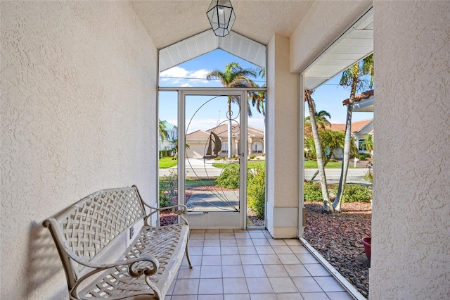 doorway to outside with a healthy amount of sunlight, light tile patterned flooring, and vaulted ceiling