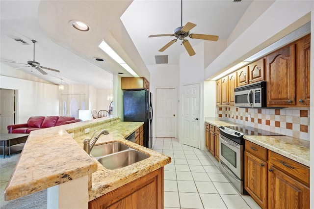 kitchen featuring sink, vaulted ceiling, decorative backsplash, light tile patterned flooring, and appliances with stainless steel finishes