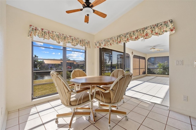 dining room with ceiling fan, light tile patterned flooring, a water view, and lofted ceiling