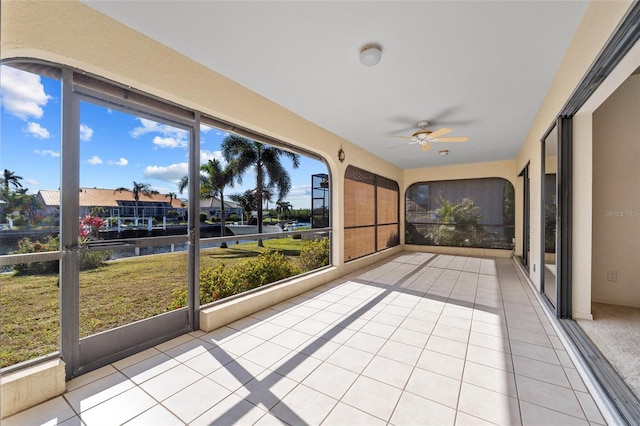 unfurnished sunroom with a water view and ceiling fan