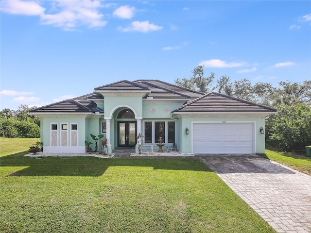 view of front of property featuring french doors, a garage, and a front lawn