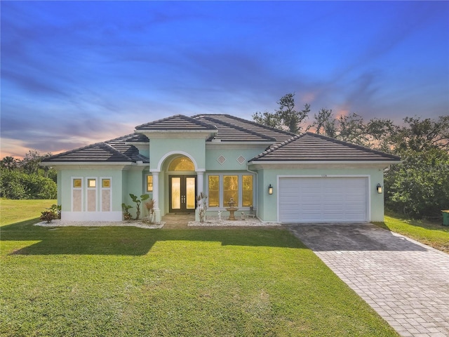 view of front facade with french doors, a yard, and a garage