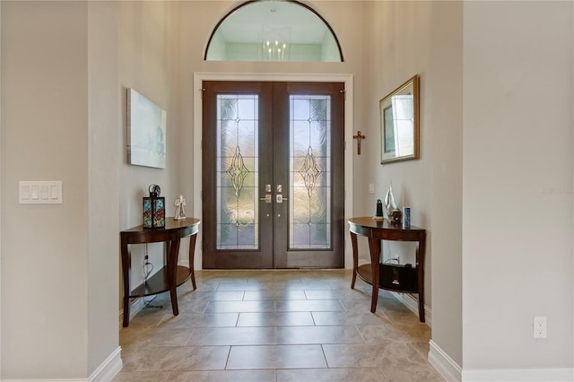 foyer featuring french doors, a notable chandelier, and light tile patterned flooring