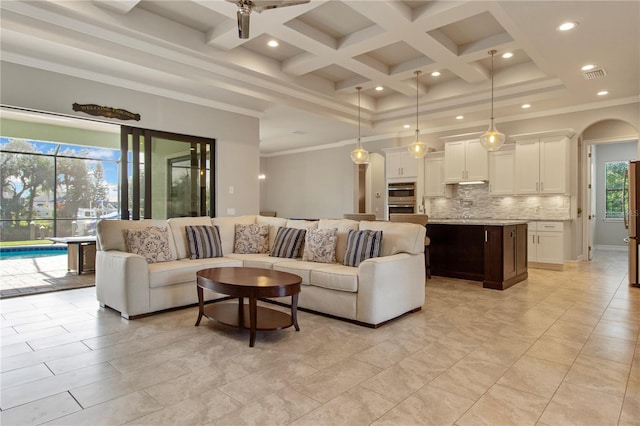 living room featuring a high ceiling, coffered ceiling, ceiling fan, ornamental molding, and beamed ceiling