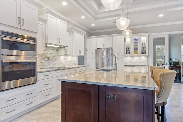 kitchen featuring decorative backsplash, ornamental molding, a breakfast bar area, and stainless steel appliances