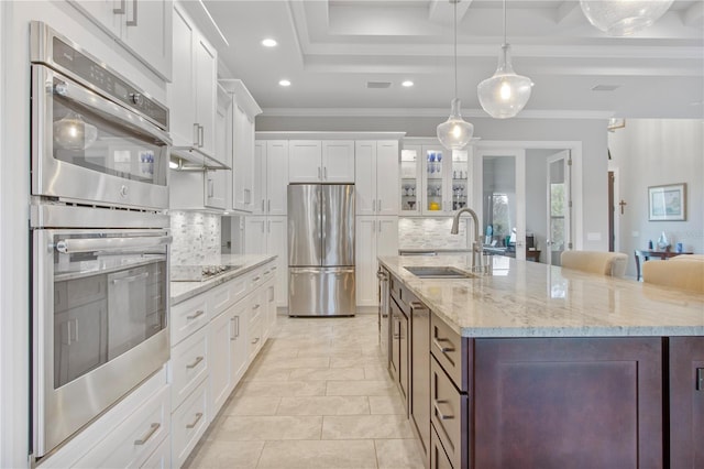 kitchen featuring stainless steel appliances, white cabinetry, tasteful backsplash, and a center island with sink