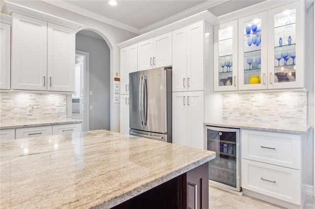 kitchen with wine cooler, stainless steel fridge, light stone countertops, tasteful backsplash, and white cabinetry