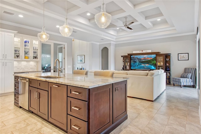 kitchen featuring coffered ceiling, a kitchen island with sink, sink, decorative light fixtures, and white cabinets