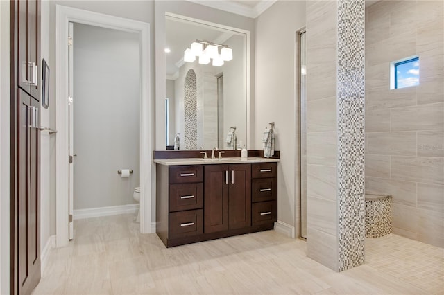 bathroom featuring tiled shower, vanity, toilet, and ornamental molding