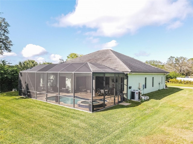 rear view of house featuring cooling unit, a swimming pool with hot tub, glass enclosure, a yard, and a patio