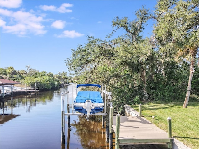 view of dock with a lawn and a water view