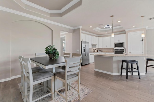 dining area featuring a raised ceiling and ornamental molding