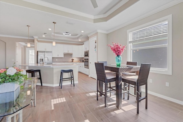 dining area with a raised ceiling and ornamental molding