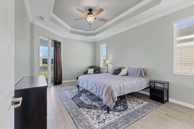 bedroom featuring light hardwood / wood-style flooring, a raised ceiling, ceiling fan, and ornamental molding