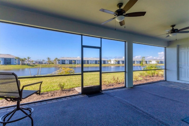 unfurnished sunroom featuring a water view and ceiling fan