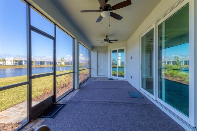 unfurnished sunroom with a water view and ceiling fan