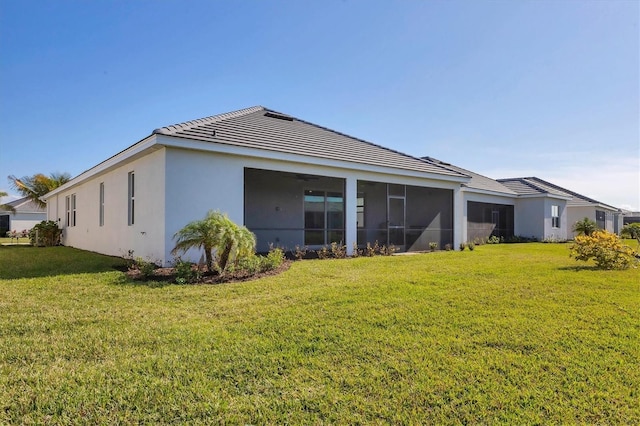 rear view of house featuring a lawn and a sunroom