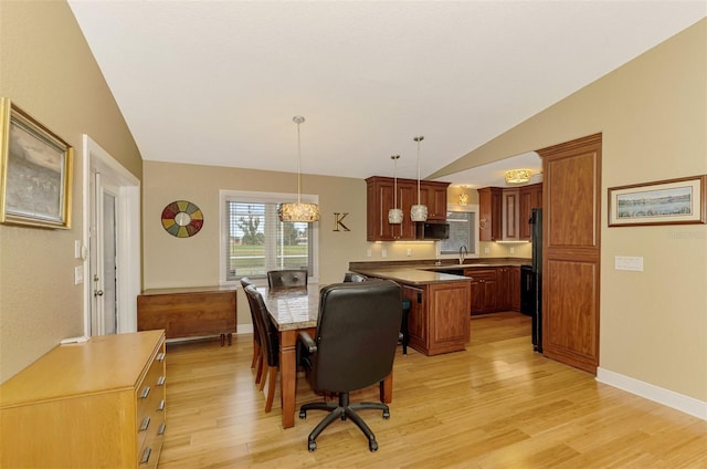 dining room featuring light wood-type flooring, lofted ceiling, and sink