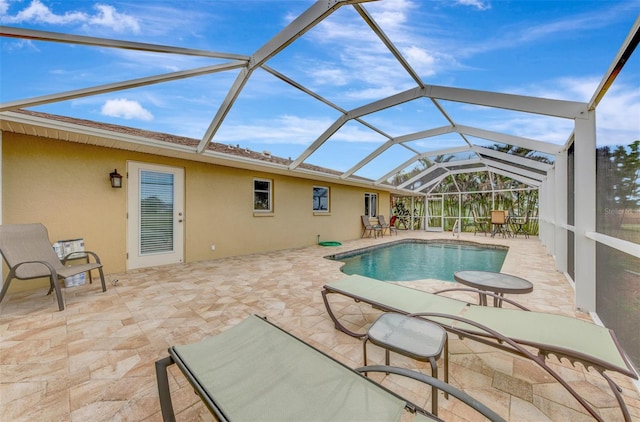 view of swimming pool featuring glass enclosure and a patio area