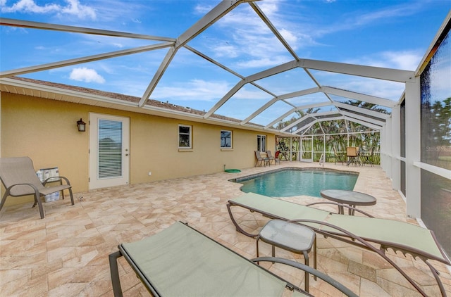 view of pool featuring glass enclosure and a patio area