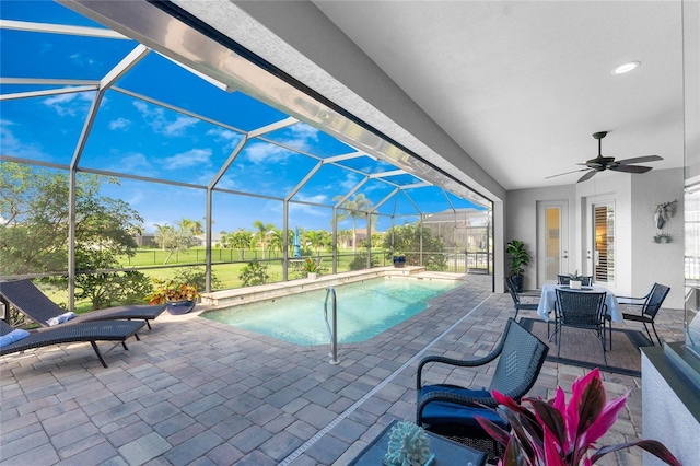 view of swimming pool with ceiling fan, a patio, and glass enclosure