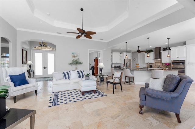 living room with french doors, a raised ceiling, ornamental molding, and ceiling fan