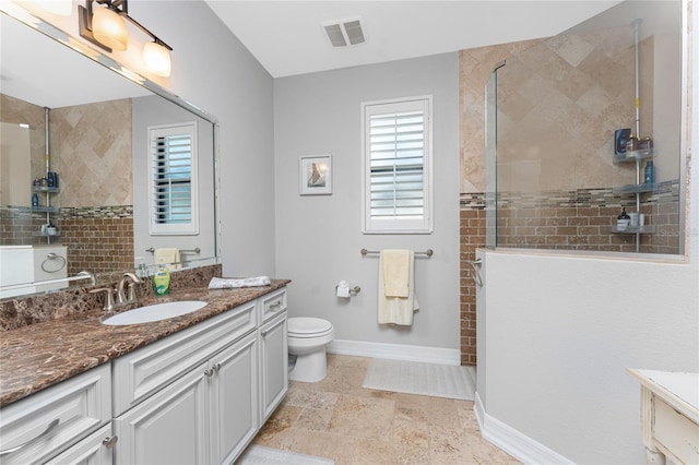 bathroom with tiled shower, vanity, and toilet