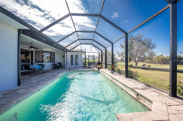 view of pool featuring a lawn, ceiling fan, glass enclosure, and a patio