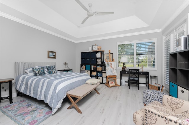 bedroom with light hardwood / wood-style floors, ceiling fan, a tray ceiling, and crown molding