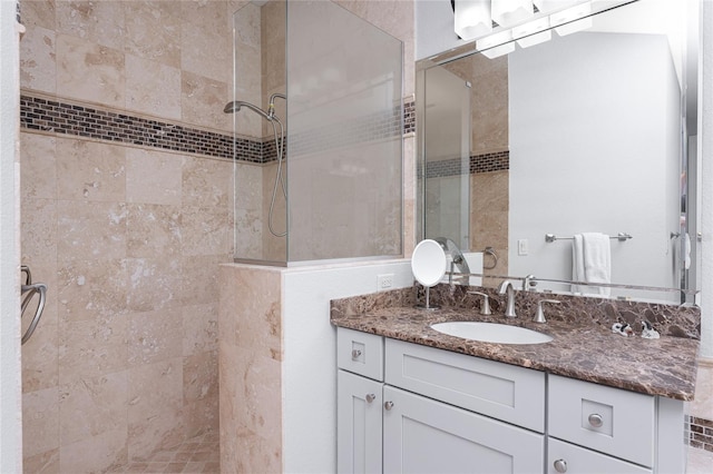 bathroom with a tile shower and vanity