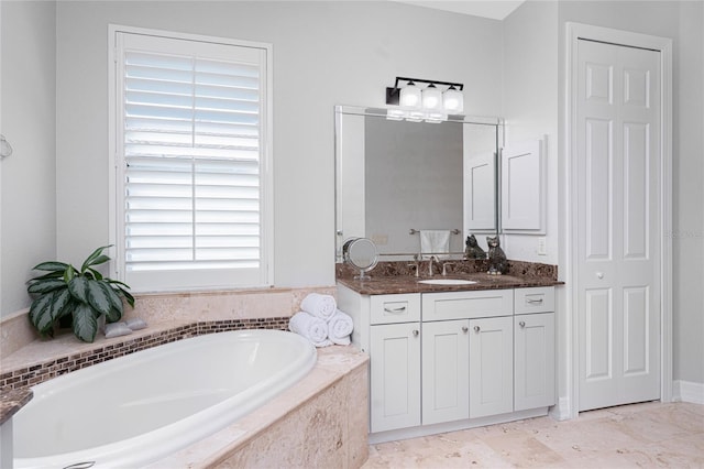 bathroom featuring tiled tub, a wealth of natural light, and vanity