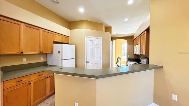 kitchen with white appliances, kitchen peninsula, and light tile patterned floors