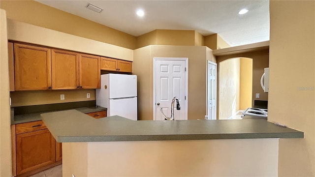 kitchen featuring kitchen peninsula, light tile patterned floors, white appliances, and sink