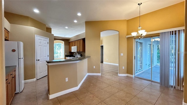 kitchen featuring white appliances, decorative light fixtures, light tile patterned floors, a notable chandelier, and kitchen peninsula