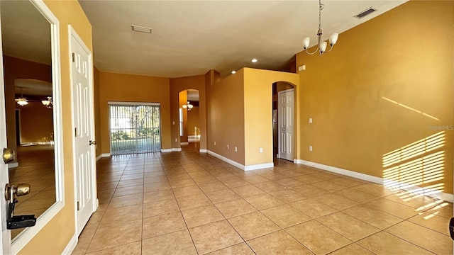 tiled spare room with ceiling fan with notable chandelier