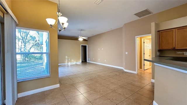 unfurnished dining area with ceiling fan with notable chandelier and light tile patterned floors