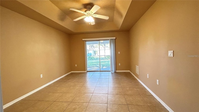 spare room with ceiling fan, light tile patterned flooring, and a tray ceiling