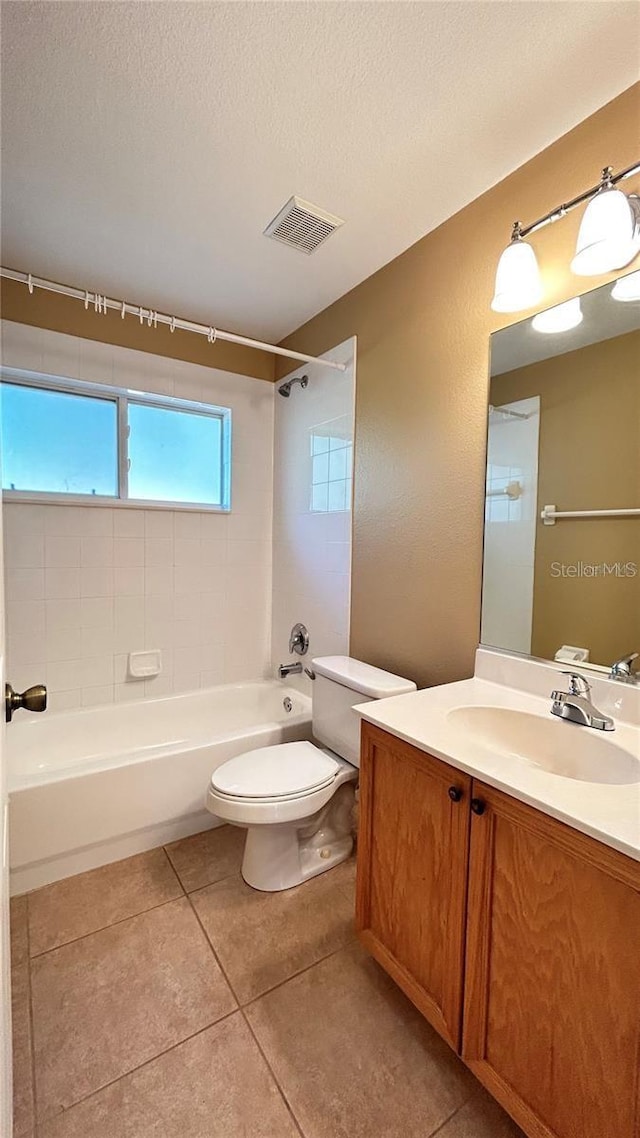 full bathroom with a textured ceiling, vanity, tile patterned flooring, toilet, and tiled shower / bath